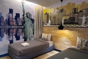 Ein Schlafzimmer mit Wandgemälde der Freiheitsstatue, einer Stadtansicht und einem Bett mit Kissen.