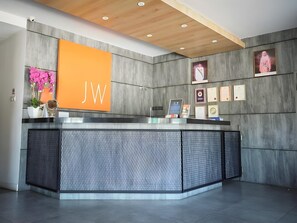 A reception desk with a modern design, featuring a prominent 'JW' sign, a framed certificate display, and a decorative plant. - 96 Boutique Hotel (Melaka)