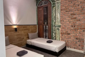 Een kamer met twee bedden, een bakstenen muur en een houten hoofdbord.