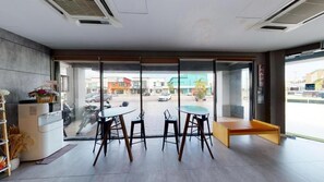 A modern interior with a glass door leading to a street view, a small seating area, and a kitchenette. - 96 Boutique Hotel (Melaka)