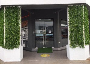 A hotel entrance with a glass door, a green mat at the entrance, and a wall with greenery on either side. - 96 Boutique Hotel (Melaka)