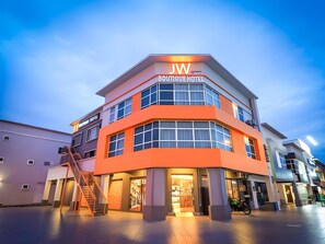 Un hôtel-boutique à plusieurs étages, reconnaissable à son enseigne bien visible indiquant « JW Boutique Hotel ».