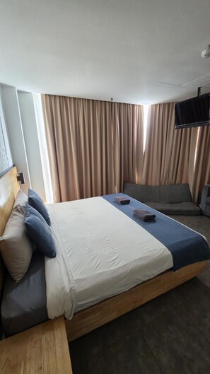 A hotel room with a bed, a sofa, a flat-screen TV, and curtains. - 96 Boutique Hotel (Melaka)