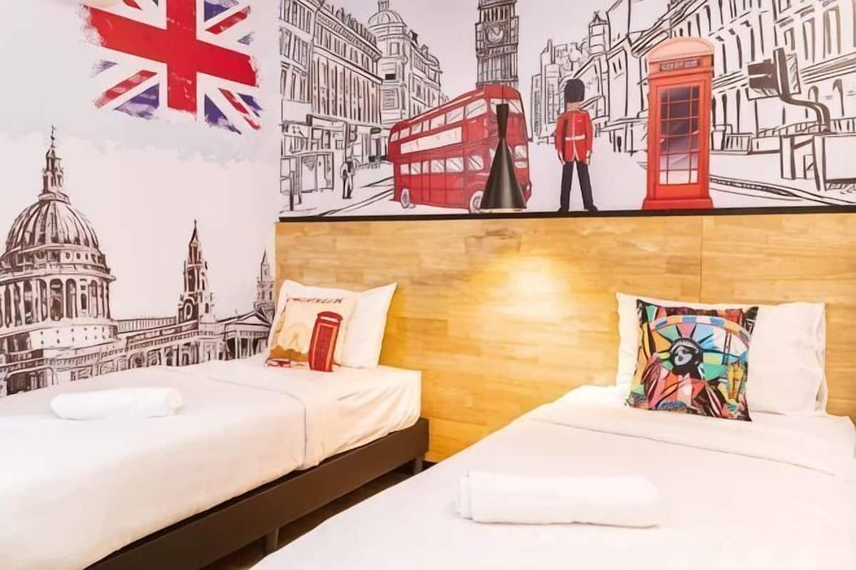 Habitación de hotel con dos camas, cabecero de madera y un mural de lugares emblemáticos de Londres.