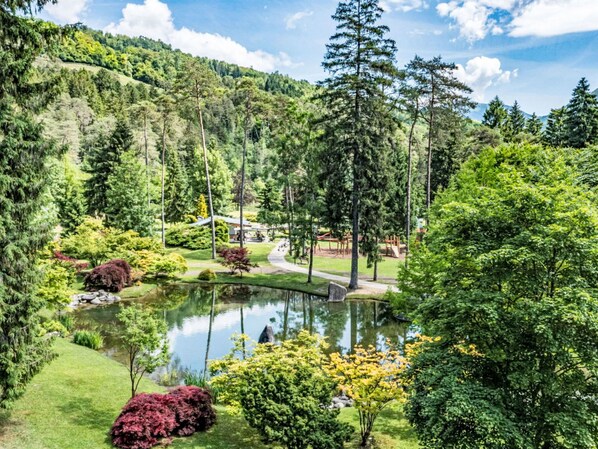 A serene landscape with a pond, lush greenery, and a playground. - Lovely apartment in villa for 5 people with WIFI, TV, terrace and panoramic view (Bleggio Superiore)