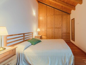 Ein Schlafzimmer mit einem hölzernen Kopfende, einem Bett mit gestreifter Bettdecke, zwei Nachttischlampen und einem Holzschrank.