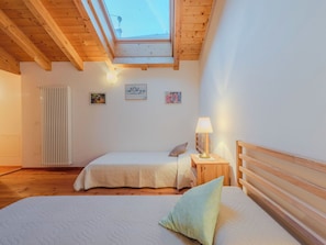 Een slaapkamer met twee bedden, dakraam, radiator en wanddecoratie.