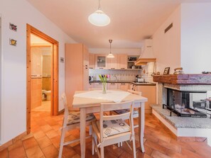 Eine kompakte Küche mit Essbereich, Holzschränken, einer gefliesten Spritzschutzwand und einem Kamin.
