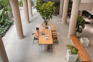 A spacious indoor area with a central table, chairs, and potted plants. - Express by M Village Hoang Van Thu, a brand of Modern Village Lifestyle (Ho Chi Minh City)