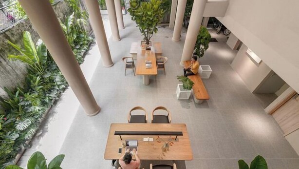 A spacious indoor area with multiple seating arrangements, including tables and chairs, surrounded by potted plants. - Express by M Village Hoang Van Thu, a brand of Modern Village Lifestyle (Ho Chi Minh City)