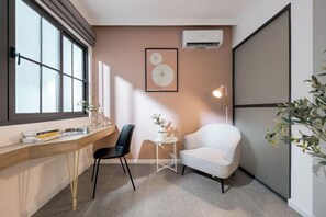 Ein modernes Zimmer mit einem Holztisch, einem schwarzen Stuhl, einem weißen Sessel und einem kleinen Tisch mit einer Vase.