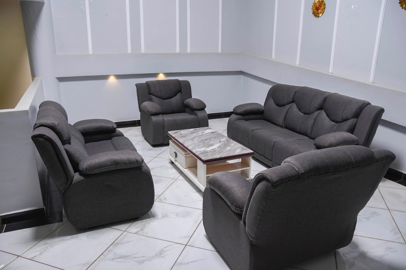 A modern living room with a grey sectional sofa, two armchairs, and a coffee table.