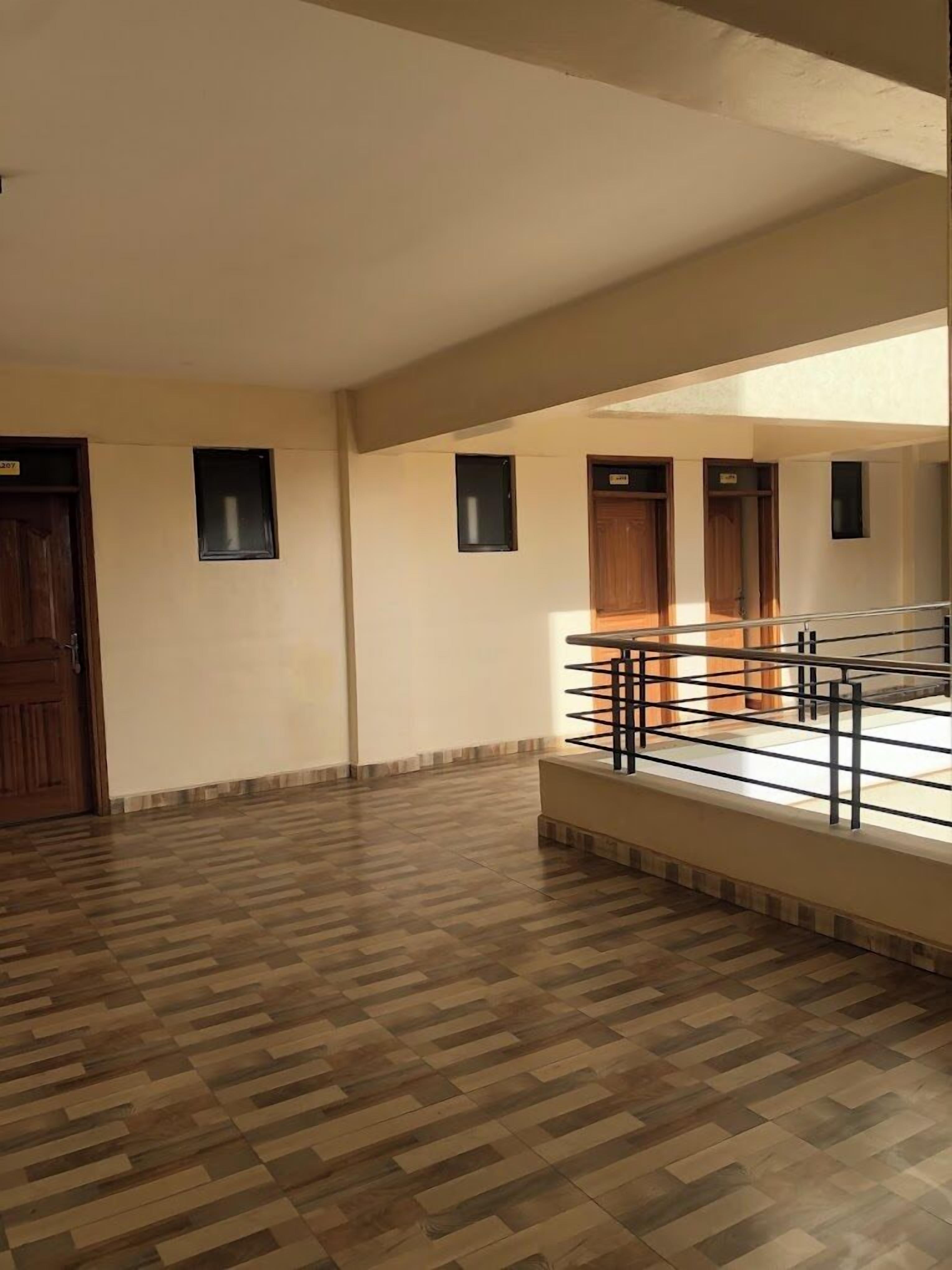 A spacious room with a wooden floor, a staircase, and a small window.