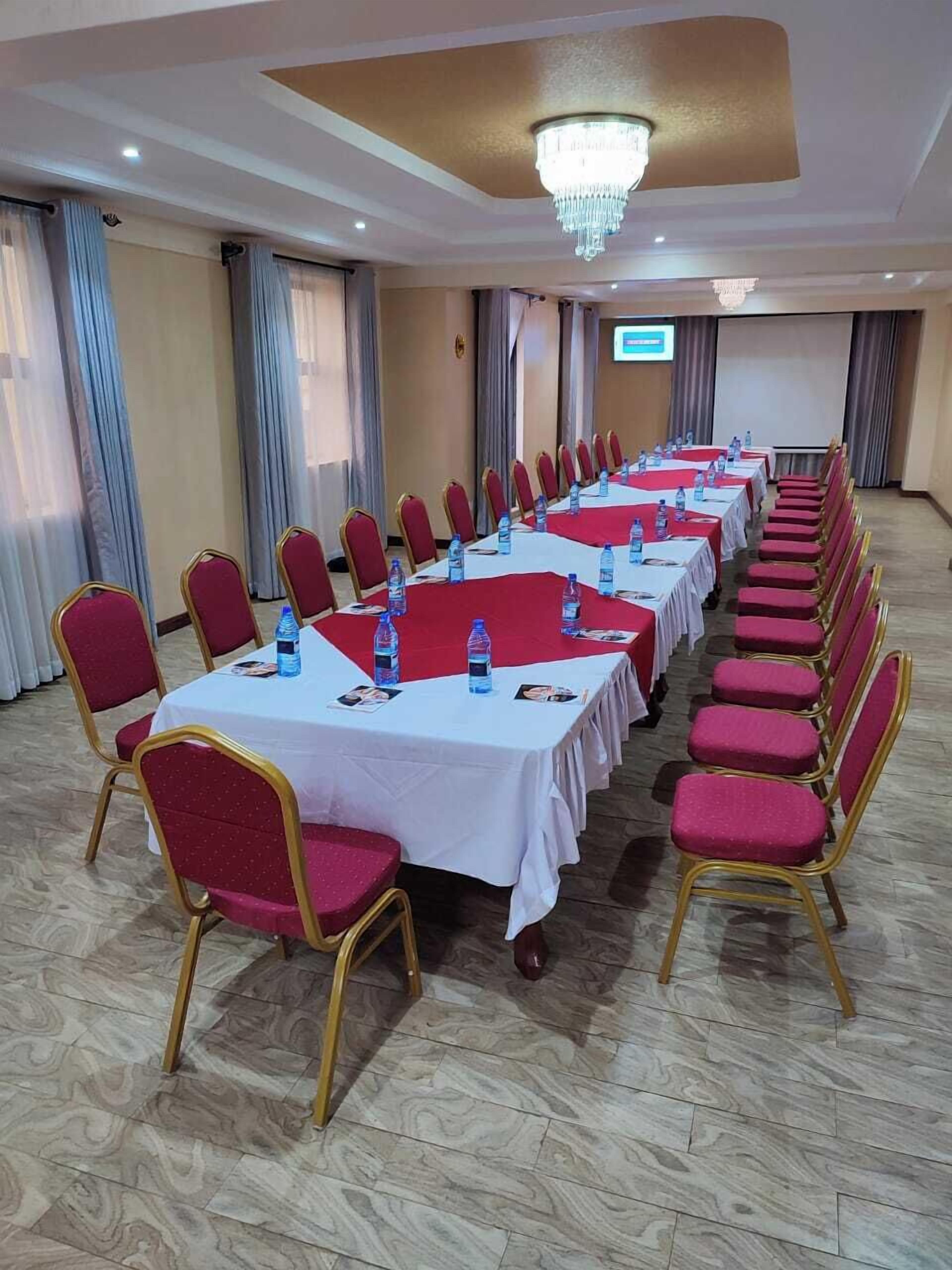 Un salón de conferencias con filas de mesas y sillas, equipado con botellas de agua y tarjetas de identificación.