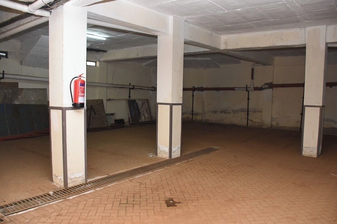 A spacious indoor area with concrete pillars, a fire extinguisher, and a vent on the floor.