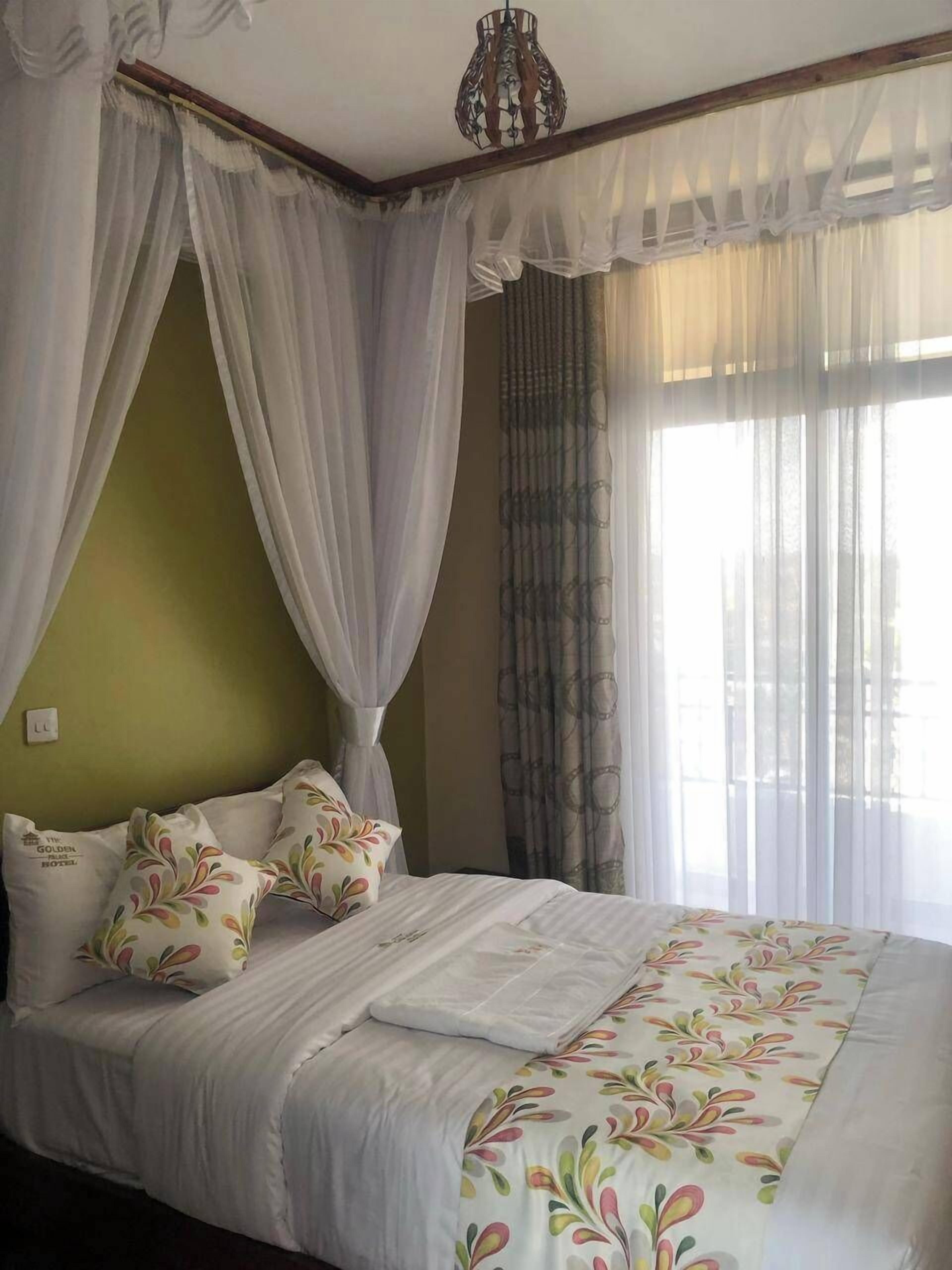 Une chambre à coucher avec un lit, des rideaux blancs et une fenêtre ornée de rideaux légers.