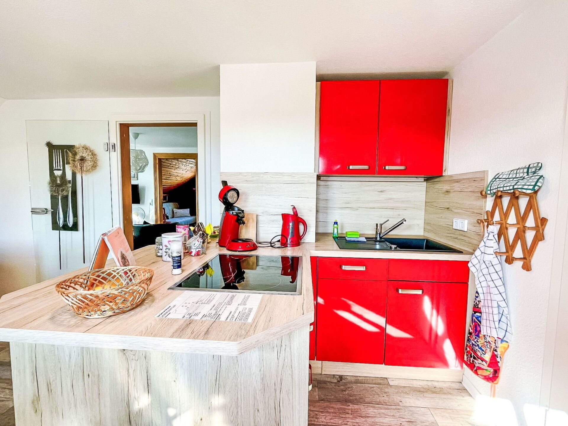 Une cuisine de taille réduite avec des meubles de rangement rouges, un plan de travail en bois et un petit évier.