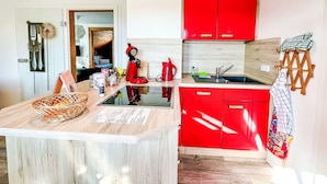 Una cocina compacta con armarios rojos, una encimera de madera y un lavamanos pequeño.