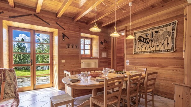 A wooden dining room with a round table, six chairs, and hanging pendant lights. - Beautiful private villa for 7 guests with WIFI, TV and pets allowed (Casone)