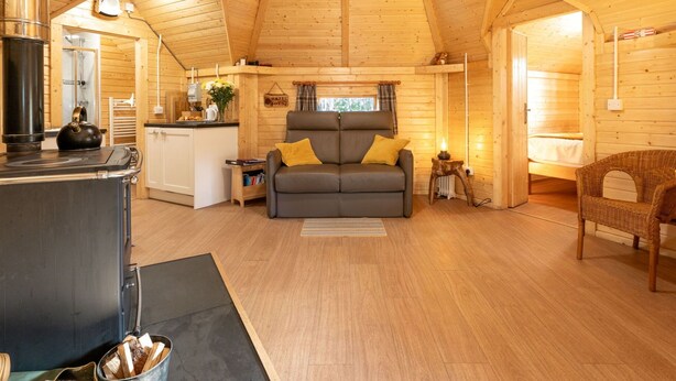 Interior acogedor de una cabaña de troncos, con cocina, sofá y comedor.