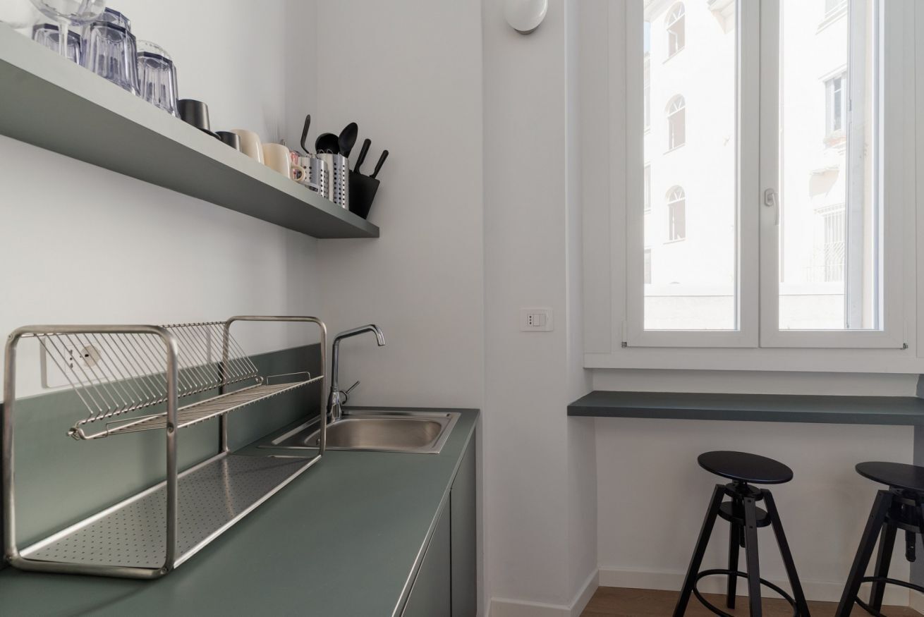 Une cuisine équipée d’une étagère en métal, d’un évier et de deux tabourets.