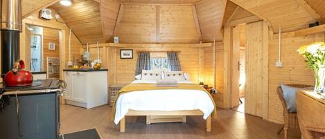 A cozy wooden cabin with a bed, a kitchenette, and a dining area.