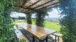 A wooden bench under a pergola with a view of a grassy field. - Cosy apartment in villa for 6 guests with WIFI, pool, TV, terrace, pets allowed and panoramic view (San Giovanni D'asso)
