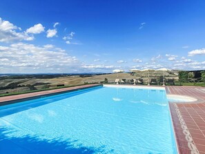 Une piscine offrant une vue sur des collines verdoyantes et un ciel dégagé.