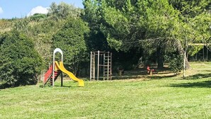 Un'area giochi con scivolo e strutture per arrampicarsi, immersa nel verde.