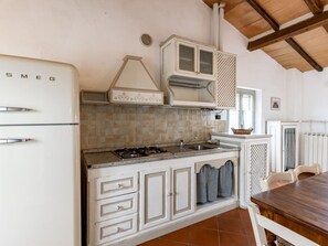 Una cocina con un refrigerador blanco, estufa a gas, alacenas y una mesa de comedor.