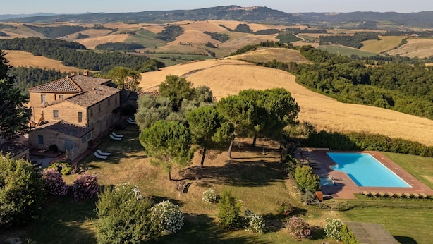 Eine Villa mit Swimmingpool, umgeben von sanften Hügeln und blauem Himmel.