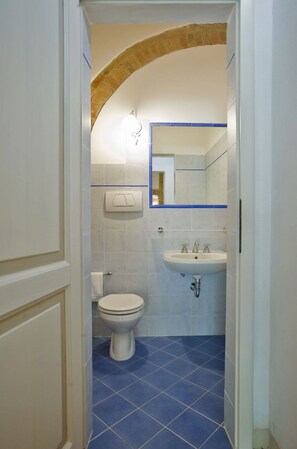 Et badeværelse med toilet, vask og spejl.