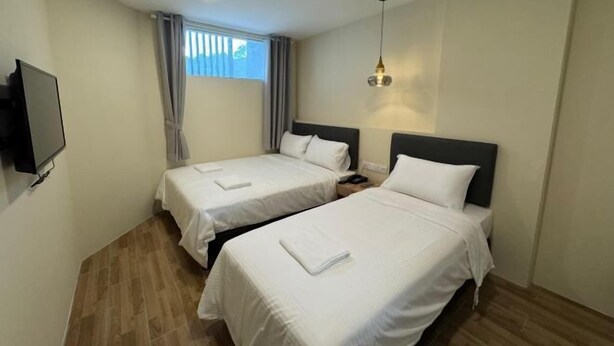 Une chambre d’hôtel avec deux lits, une télévision, une fenêtre avec des rideaux et un luminaire suspendu.