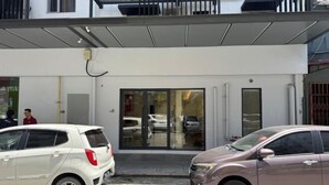 Un bâtiment avec une entrée en verre et deux voitures garées devant.