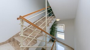 A staircase with wooden handrails, marble steps, and a potted plant.
