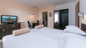 A hotel room with a bed, a desk, a television, and a wardrobe.