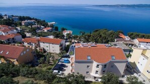 A coastal residential area with buildings, a clear view of the sea, and a hilly landscape in the background. - Apartments Relax Brela - Two Bedroom Apartment (Brela)