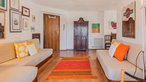 Ein Wohnzimmer mit zwei Sofas, einem Holzschrank und einem roten Teppich.