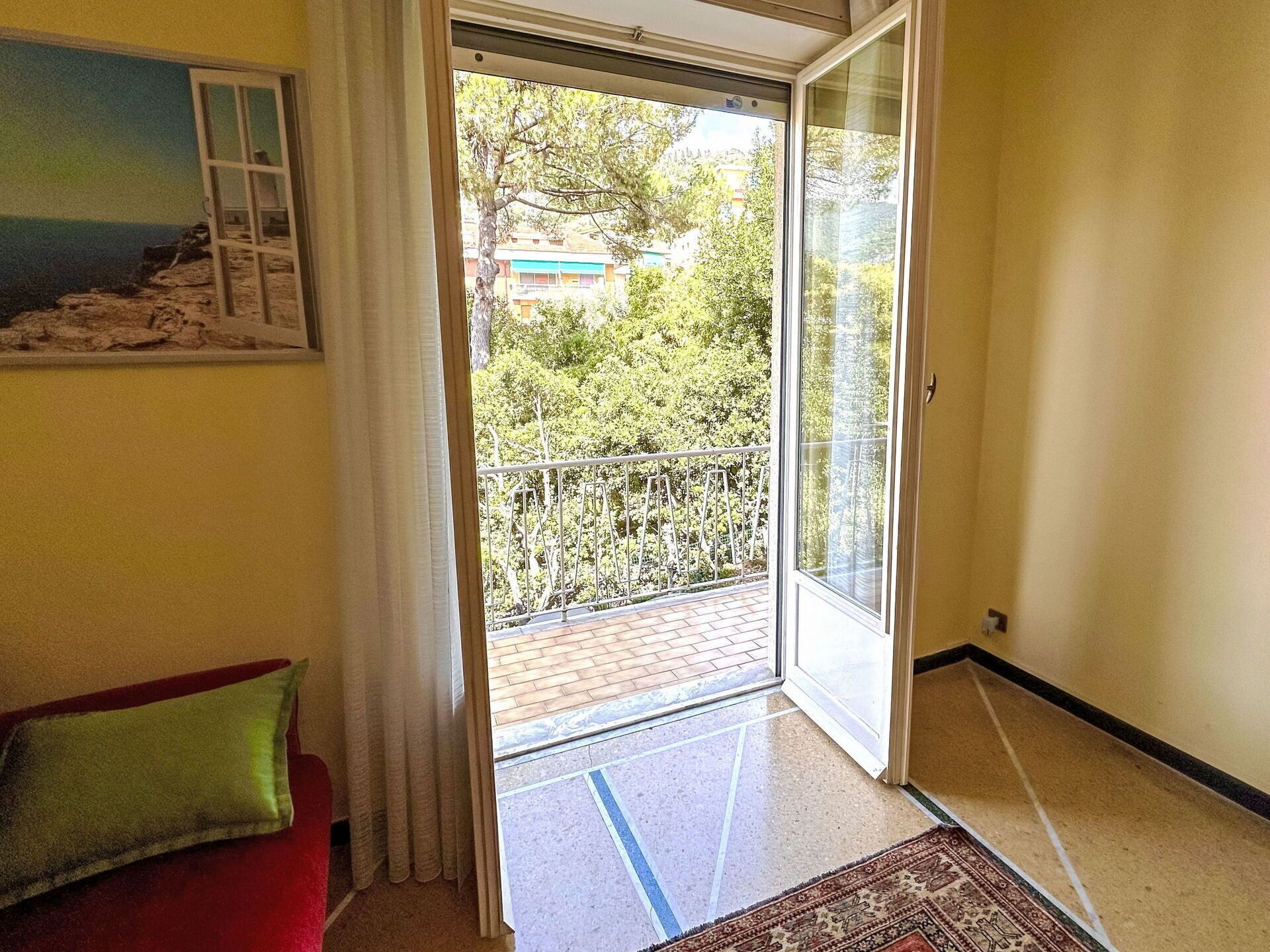 A room with a sliding glass door leading to a balcony with a metal railing.