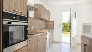 Eine moderne Küche mit Holzausstattung, einem Backofen und einem Geschirrspüler.