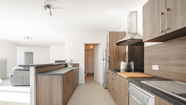 Eine moderne Küche mit Holzausstattung, einer zentralen Kochinsel, einem eingebauten Geschirrspüler und einer Edelstahl-Dunstabzugshaube.