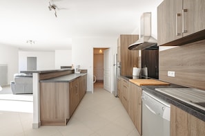 Una cocina moderna con armarios de madera, una isla central, un lavavajillas empotrado y una campana extractora de acero inoxidable.