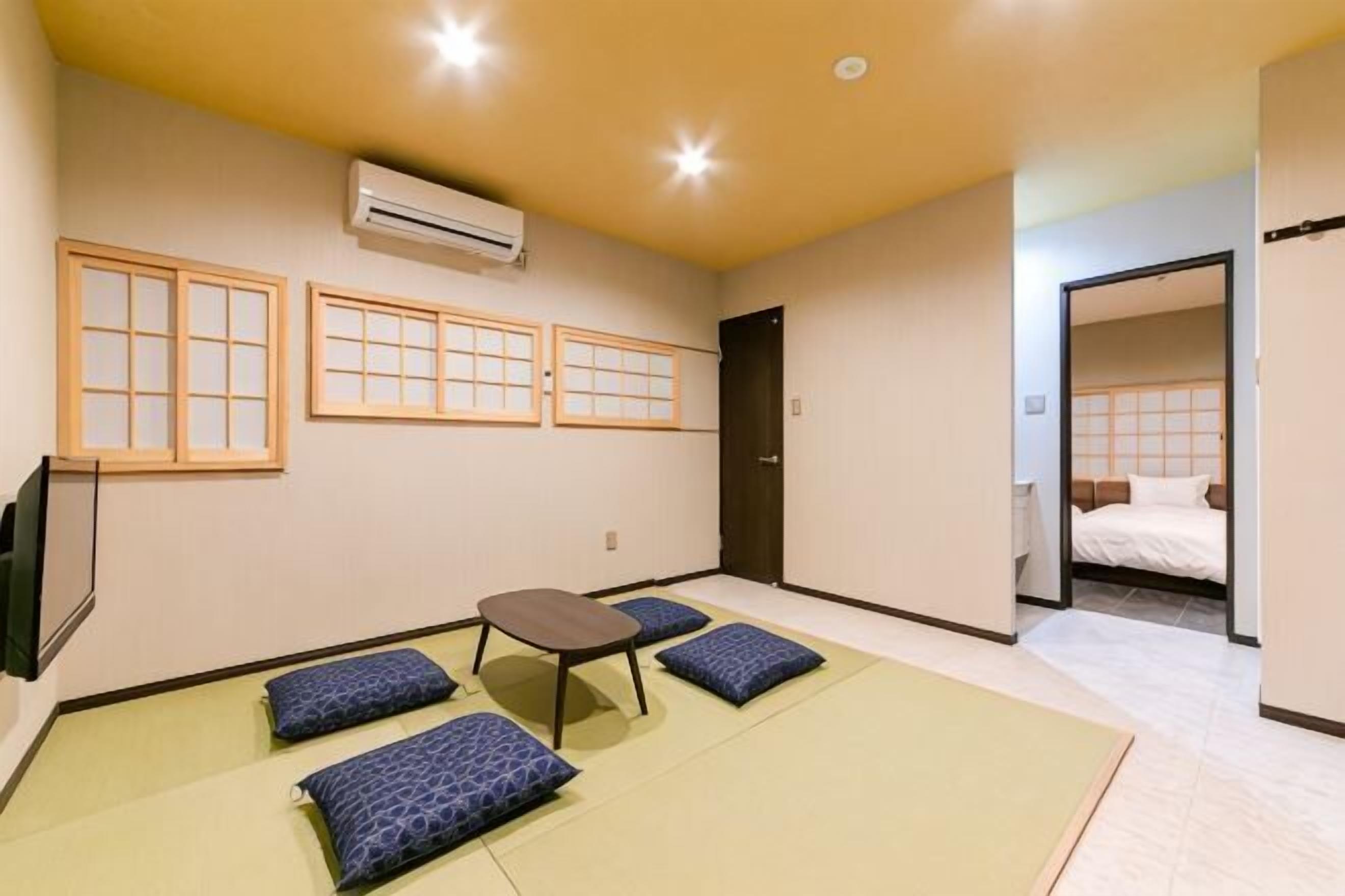 A room with tatami mats, a futon bed, a small table, and a TV.