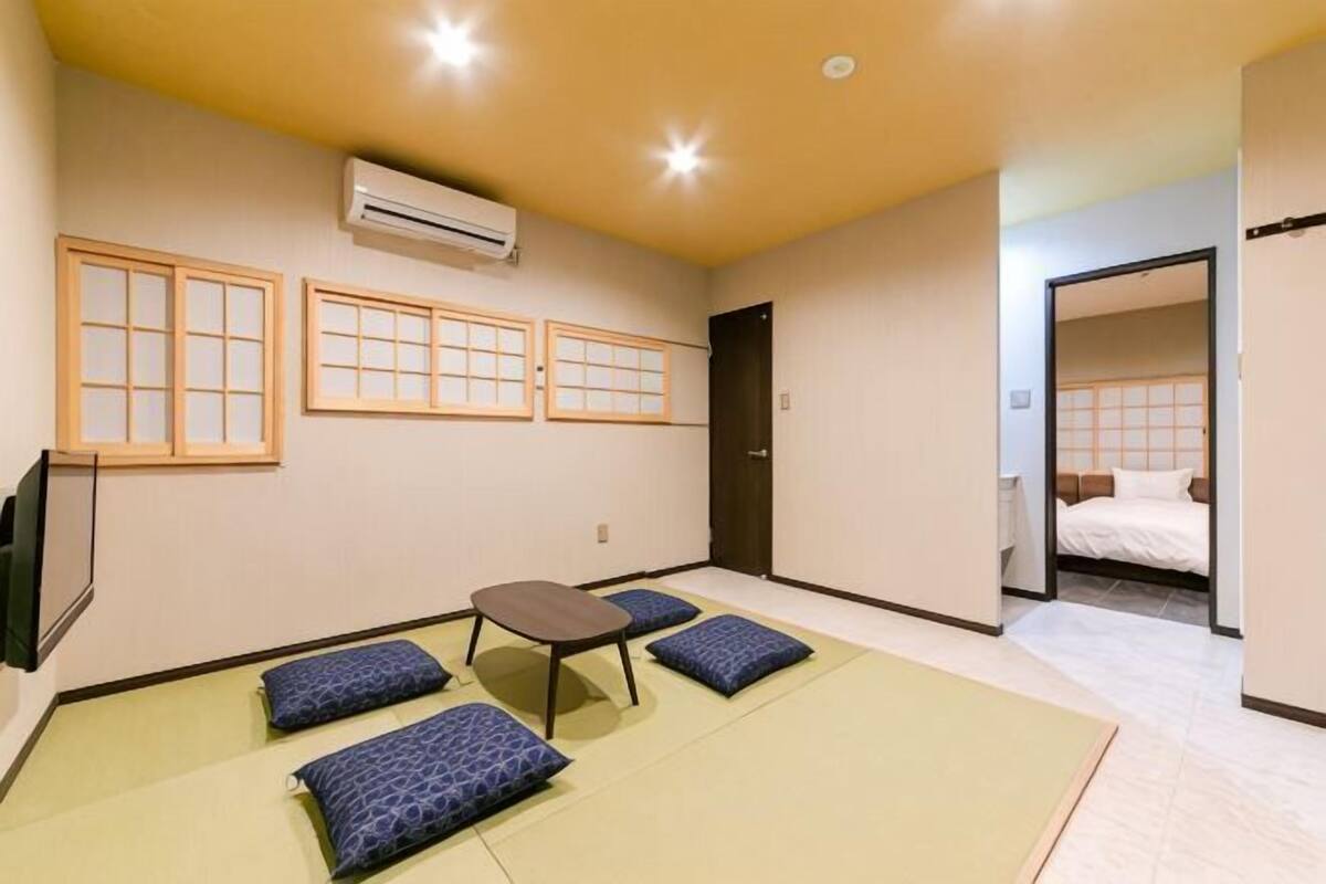 Habitación con esteras de tatami, futón, una mesita y televisión.