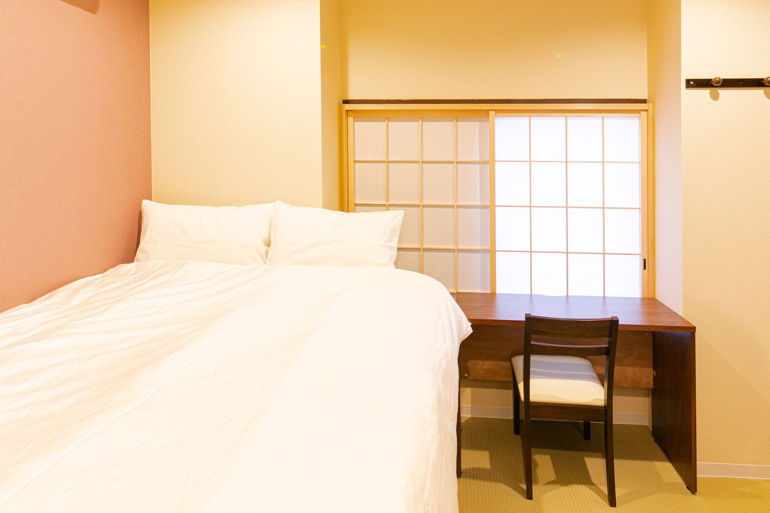 A hotel room with a bed, a desk, and a chair.