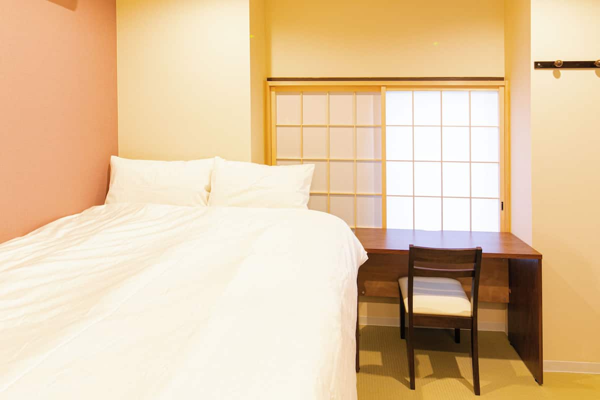 Un dormitorio con cama, escritorio y silla.