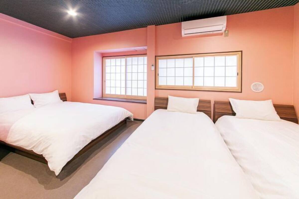 Habitación de hotel con dos camas, ventana con vistas y aire acondicionado.