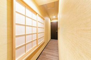 Un pasillo con piso de madera, una puerta corredera con paneles de vidrio esmerilado y una puerta de madera al final.