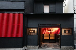En bygning med sort facade, et rødt lodret panel og en traditionel japansk indgang med skydedøre.