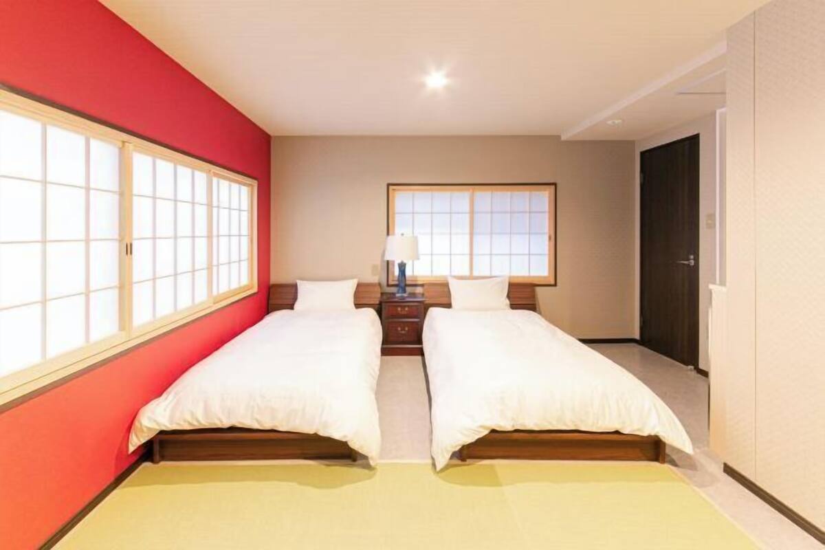 Una habitación con dos camas, una mesita de noche, una lámpara y una ventana.